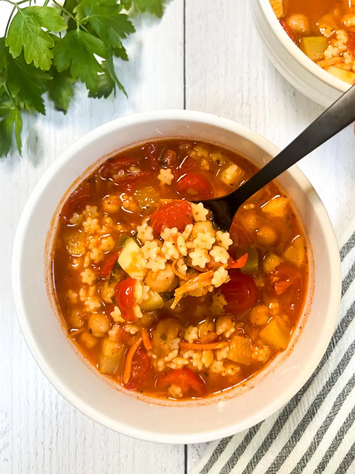 Easy vegan minestrone soup in a white bowl on white rustic table.