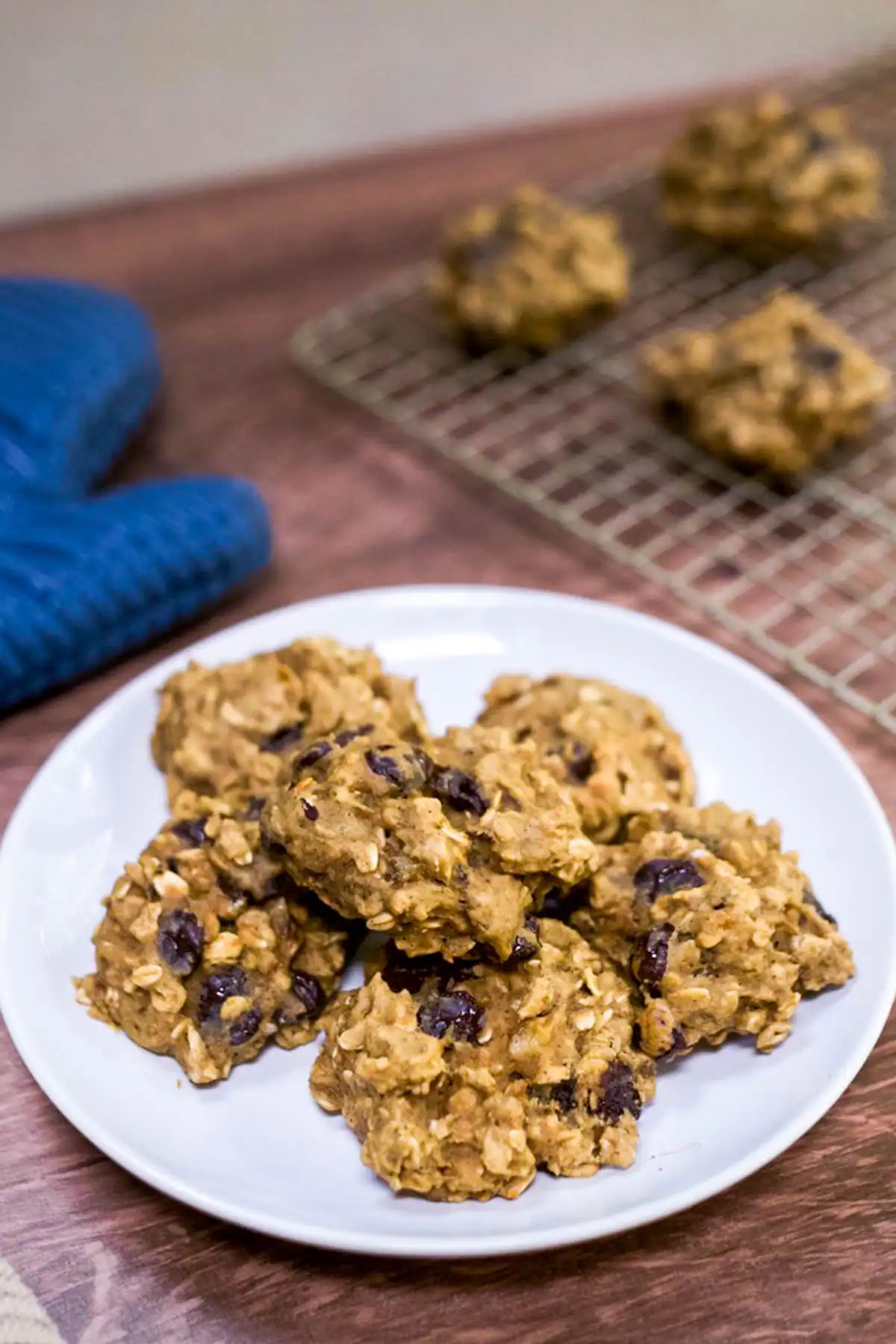 Healthy vegan breakfast cookies on a white plate with a cooling rack in the background.