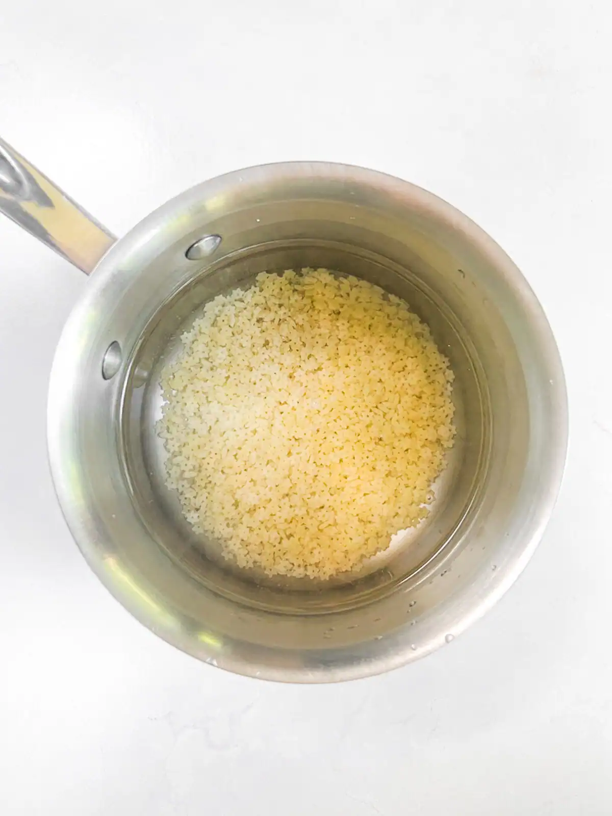 Pasta and water in a stainless steel pot.