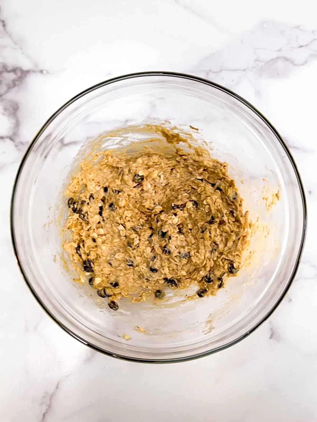 Creamy vegan cookie dough with oats and chocolate chips in a glass bowl.