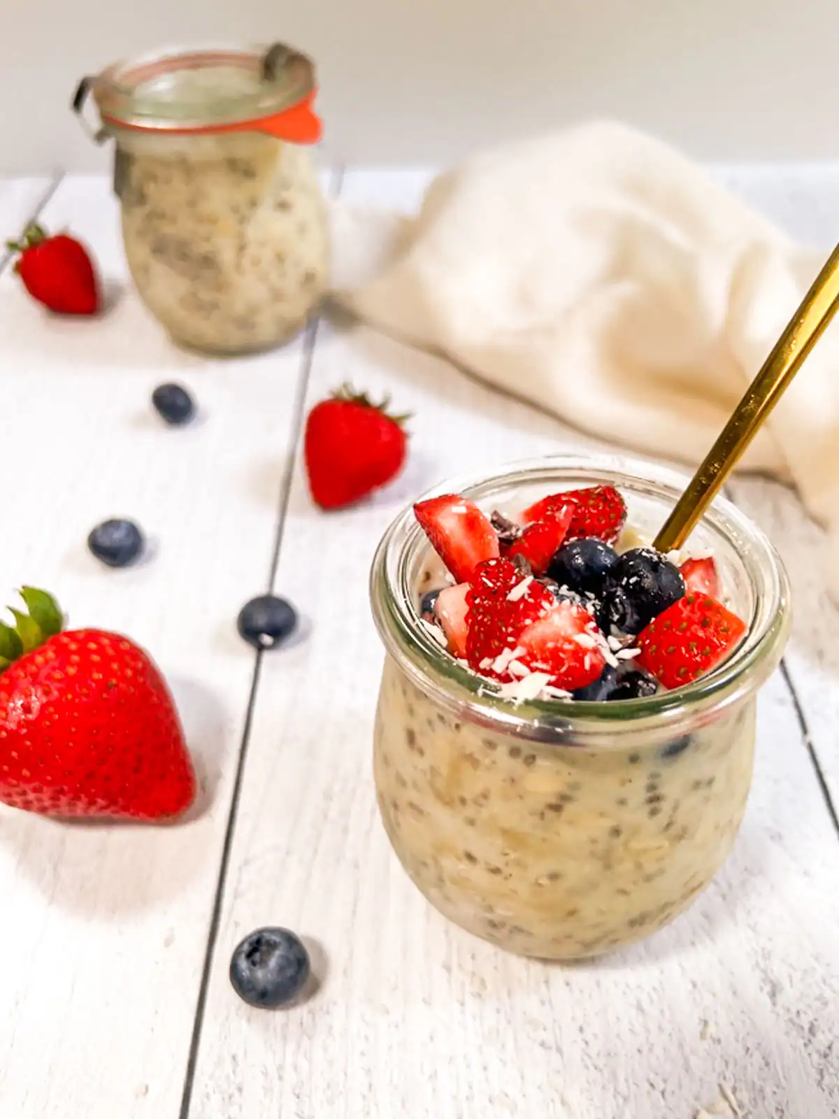 Creamy plant-based overnight oats topped with fresh strawberries and blueberries.