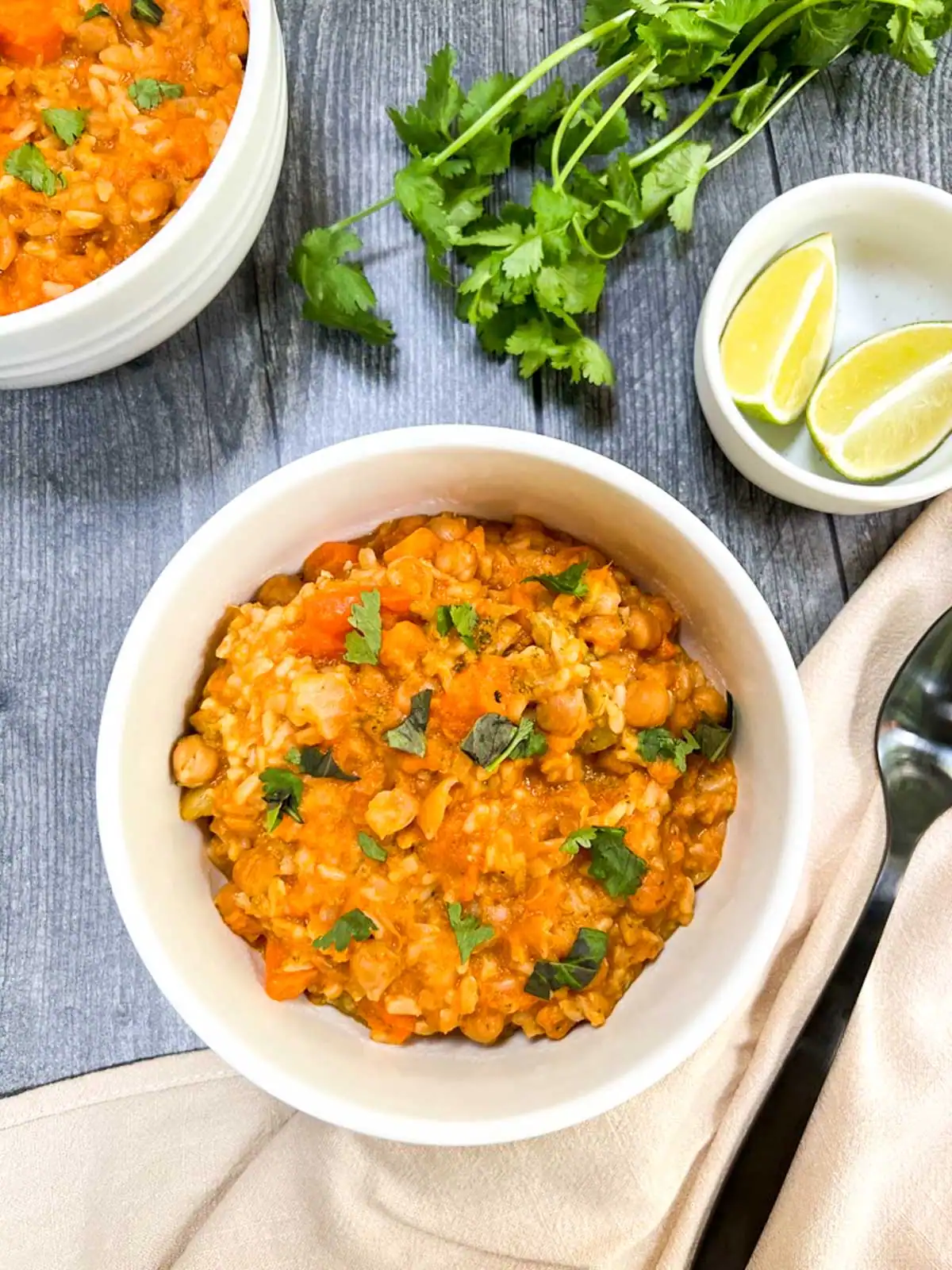 Bowls of vegan Instant Pot red curry with fresh cilantro and lime wedges.