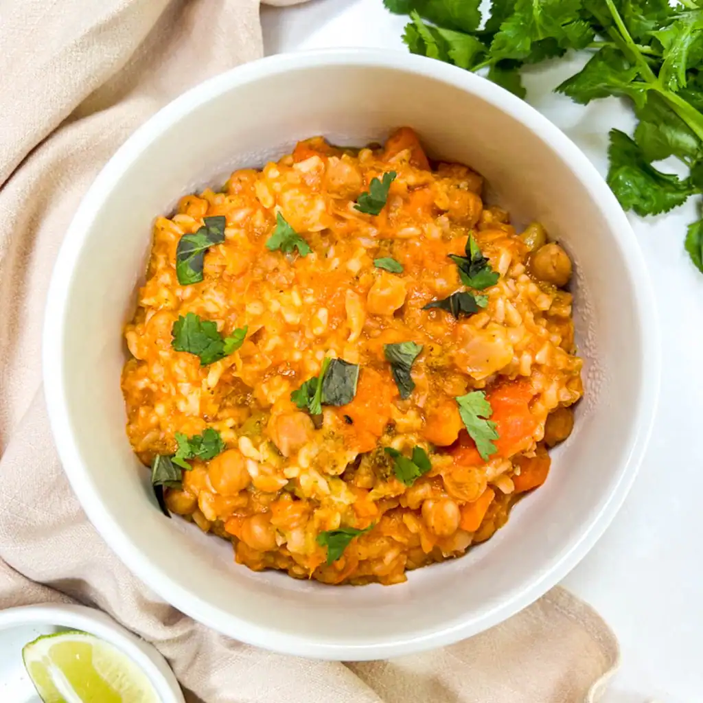 Vegan Instant Pot red curry with chickpeas and rice in a white bowl.