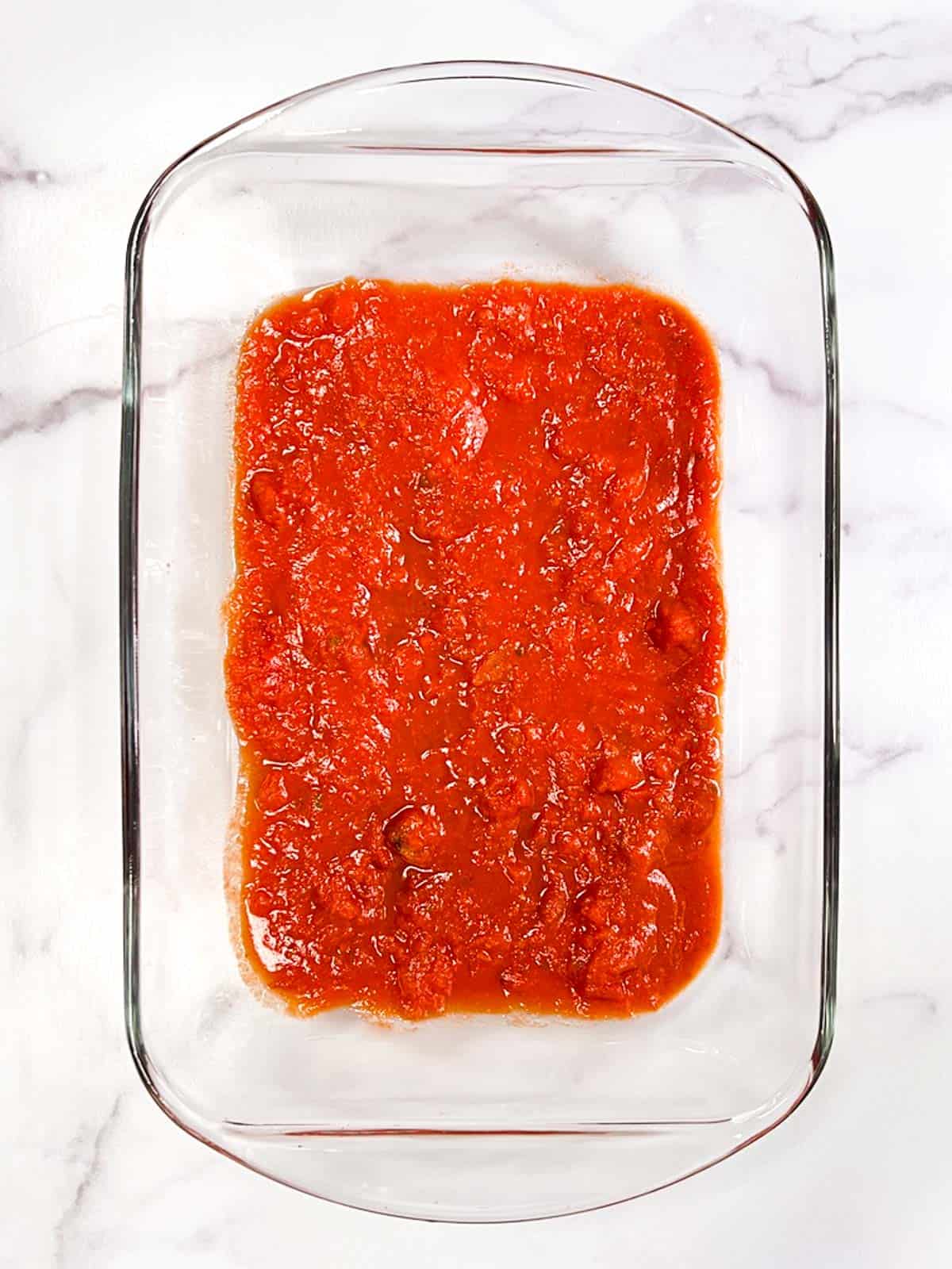 Vegan tomato sauce in a clear glass casserole dish.