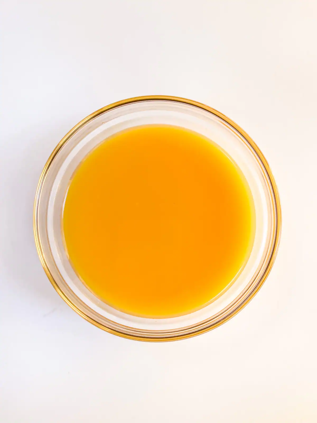 Wet ingredients for vegan orange muffins in a glass bowl.