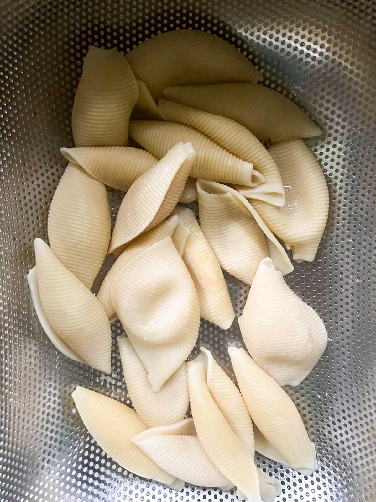 Cooked pasta shells draining in a colander.