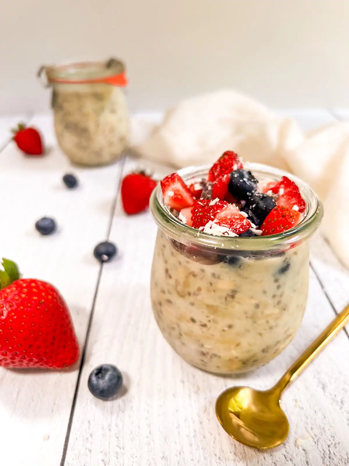 Creamy plant-based overnight oats topped with fresh strawberries and blueberries.