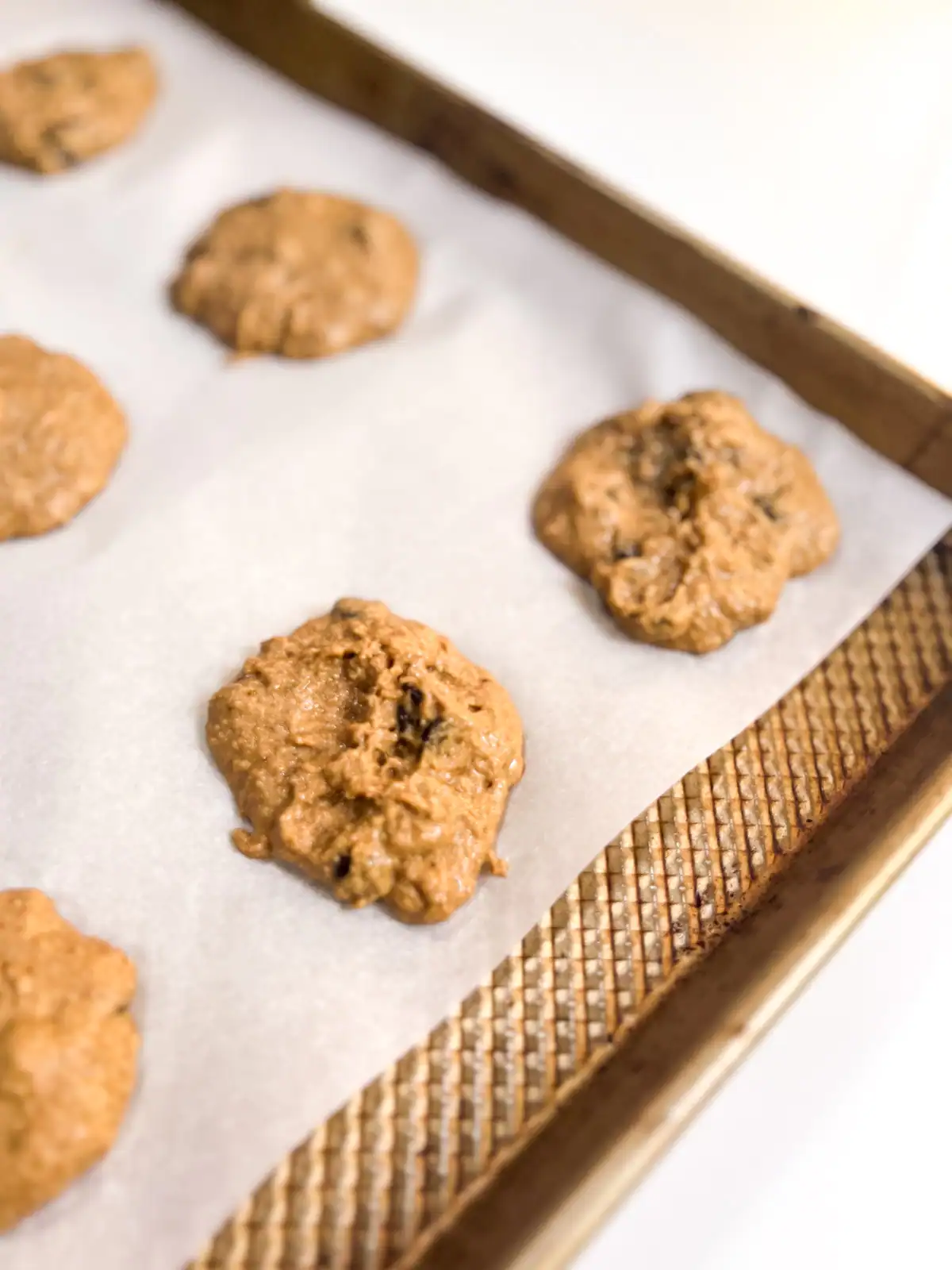 Gluten-free vegan chocolate chip cookie dough in rounds on a baking sheet, ready for the oven.