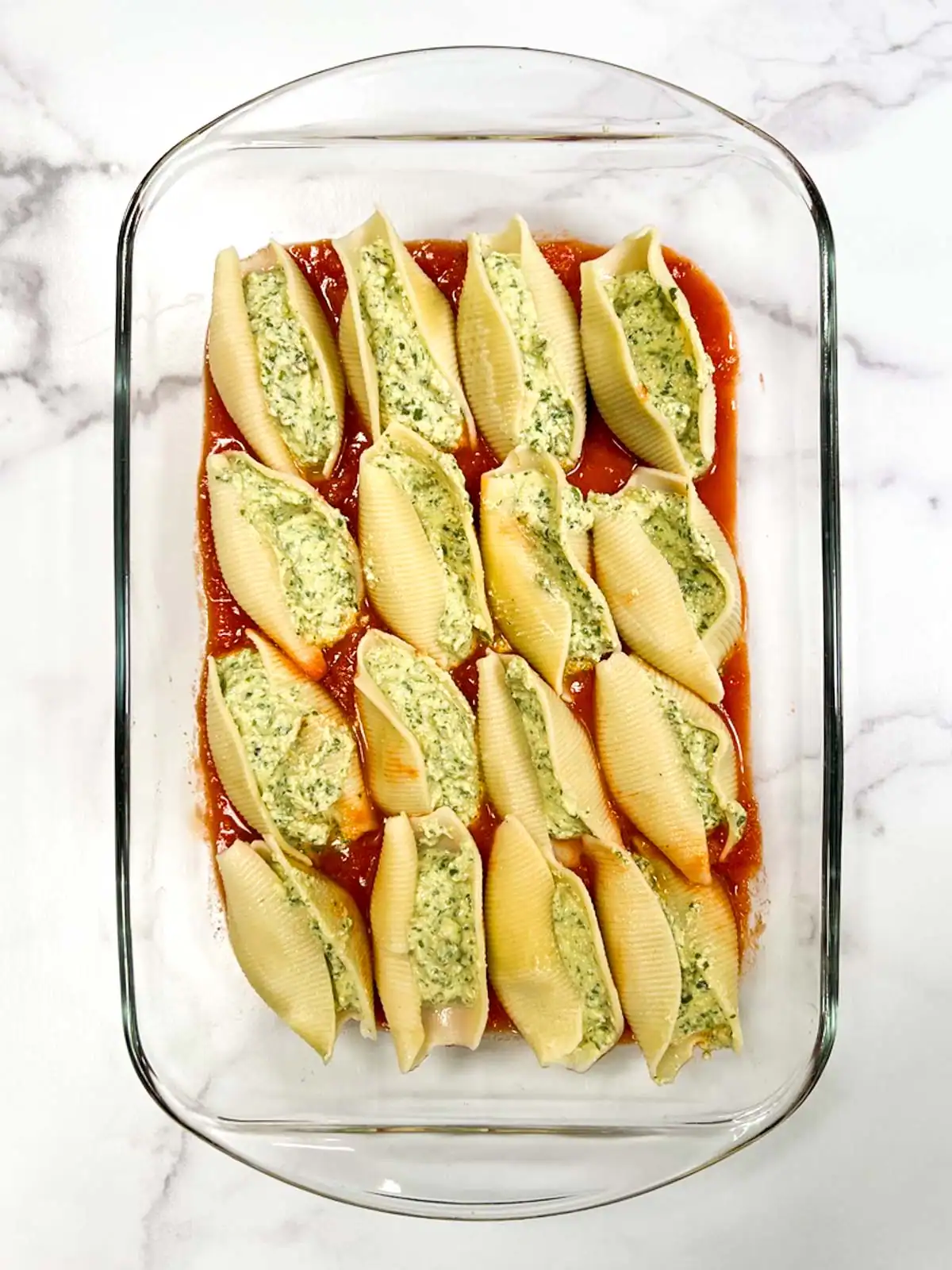Vegan stuffed shells with whipped spinach tofu ricotta in a glass dish.