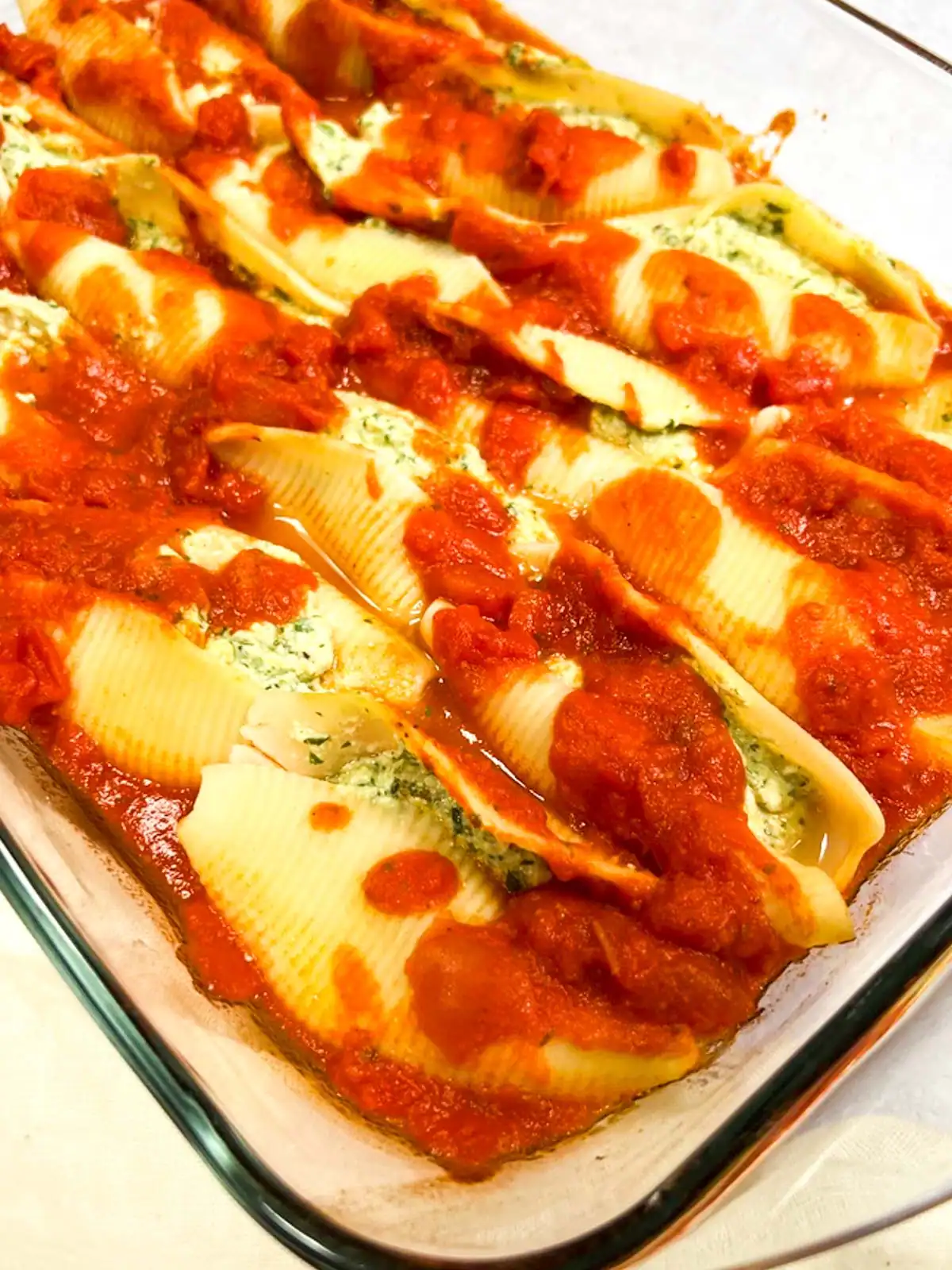 Creamy vegan stuffed pasta shells with spinach and whipped tofu ricotta in marinara sauce.