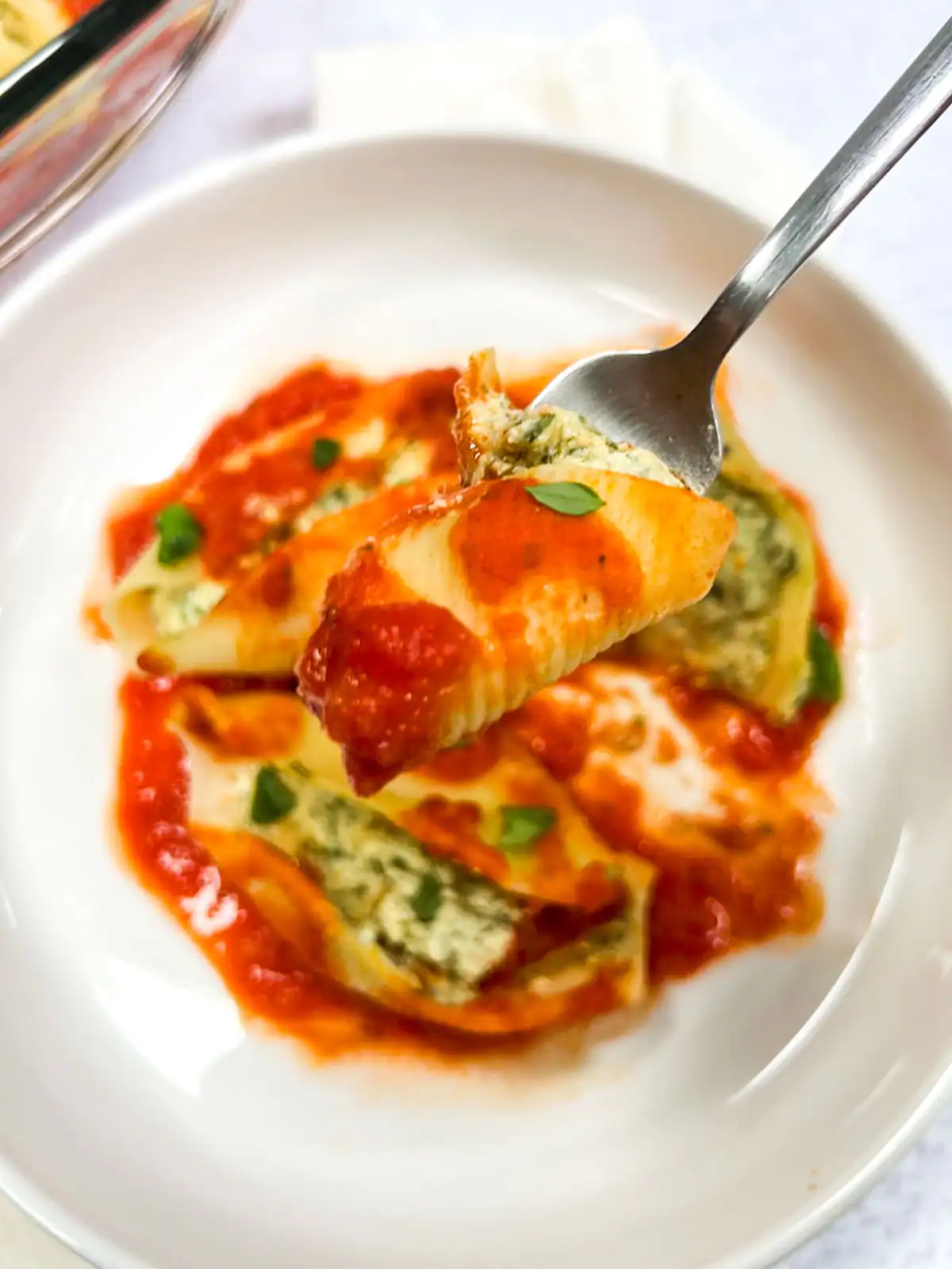 Creamy vegan stuffed pasta shells with tomato sauce and spinach tofu ricotta.