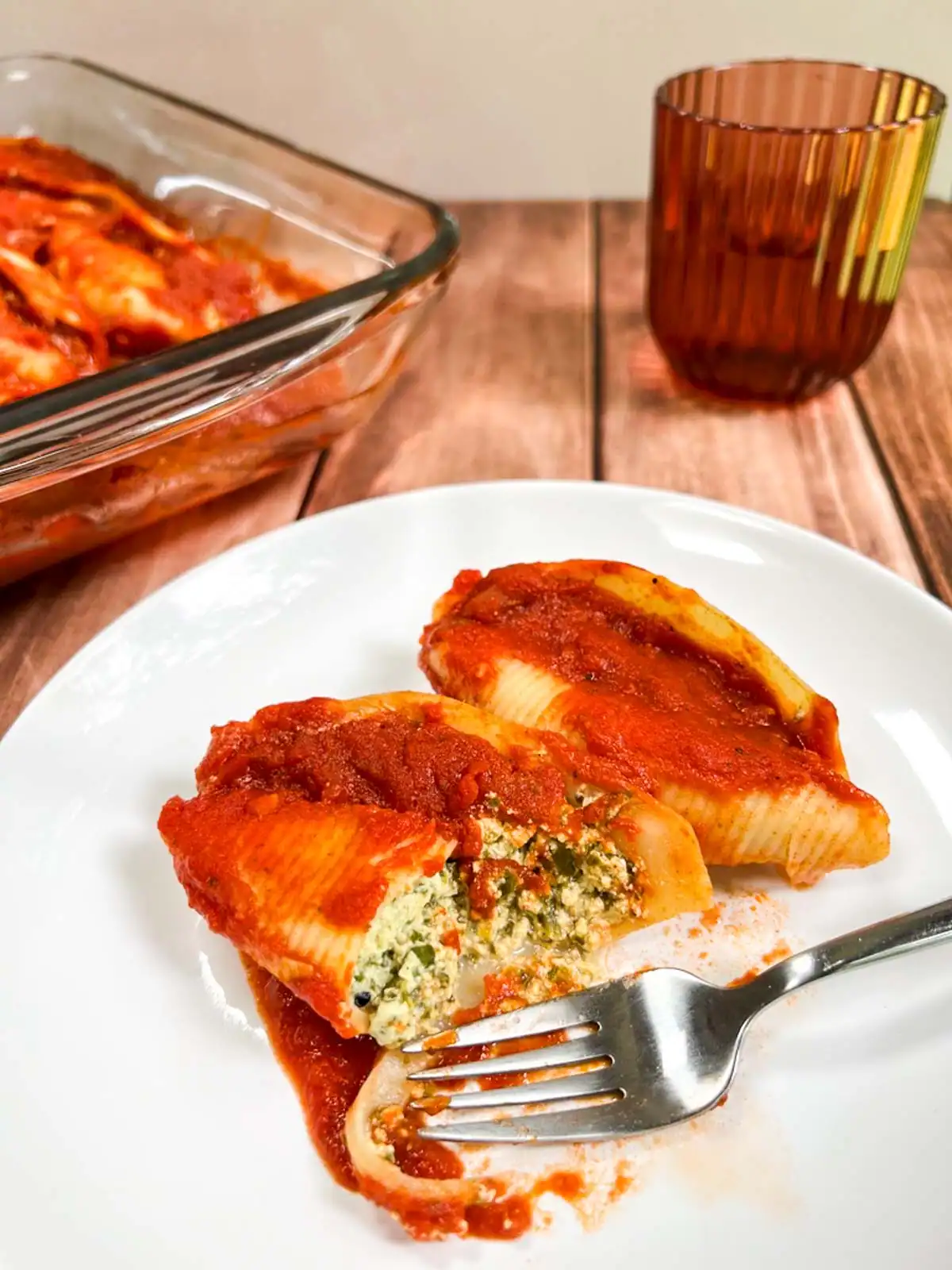 Vegan stuffed pasta shells with spinach, herbs, and vegan cheese filling on a white plate.