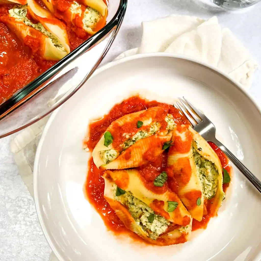 Vegan stuffed pasta shells with spinach tofu ricotta, topped with marinara sauce.