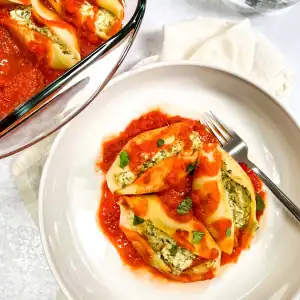 Vegan stuffed pasta shells with spinach tofu ricotta, topped with marinara sauce.