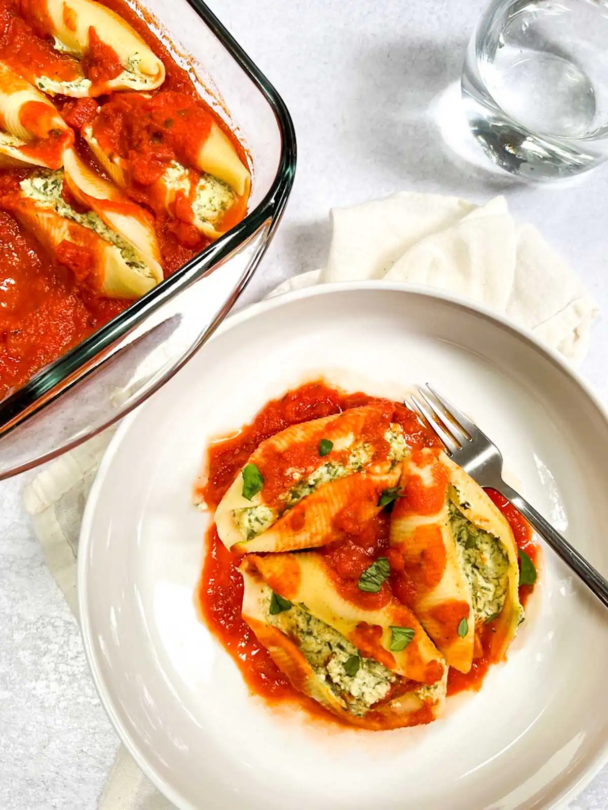Vegan stuffed pasta shells with spinach tofu ricotta, topped with marinara sauce.