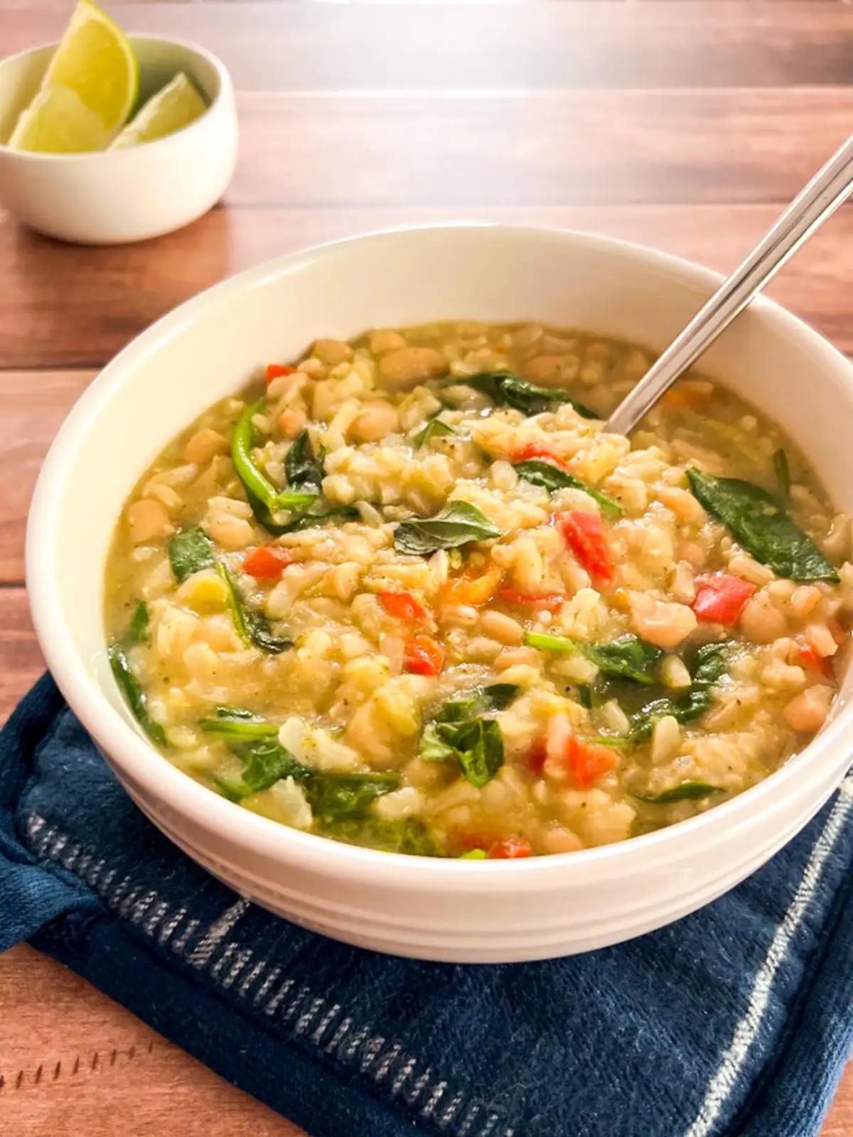 Creamy Instant Pot vegan green curry rice in a white bowl with lime wedges in the background.