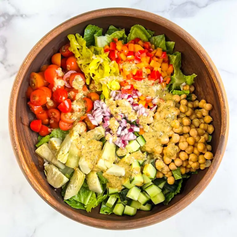 Colorful salad with homemade vegan Italian dressing in a wooden bowl.