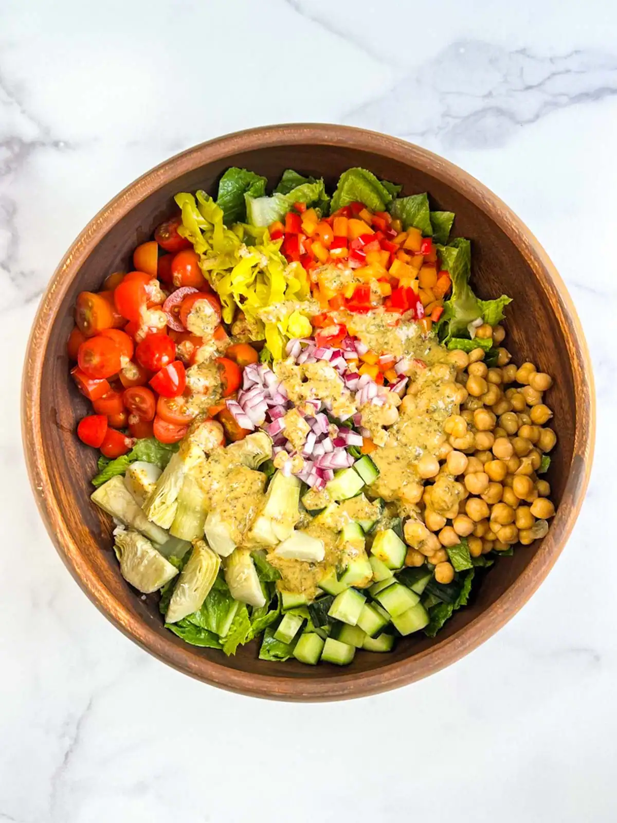 Colorful salad with homemade vegan Italian dressing in a wooden bowl.