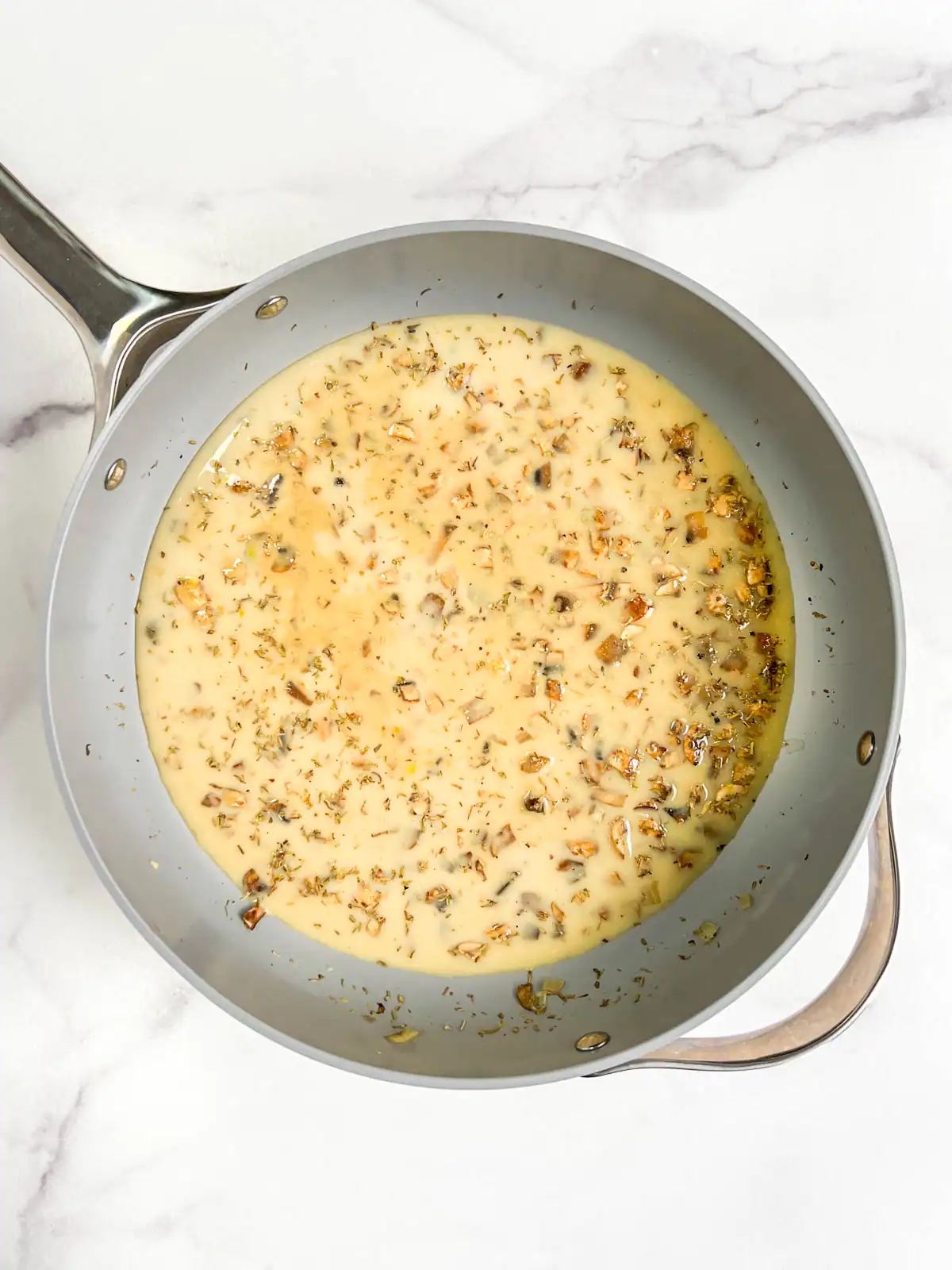 Vegetable broth and soy milk added to skillet to make creamy vegan green bean casserole sauce.
