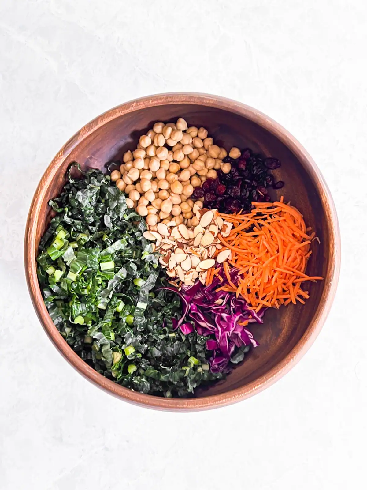 Ingredients for vegan quinoa kale salad with chickpeas and cranberries in wooden bowl.