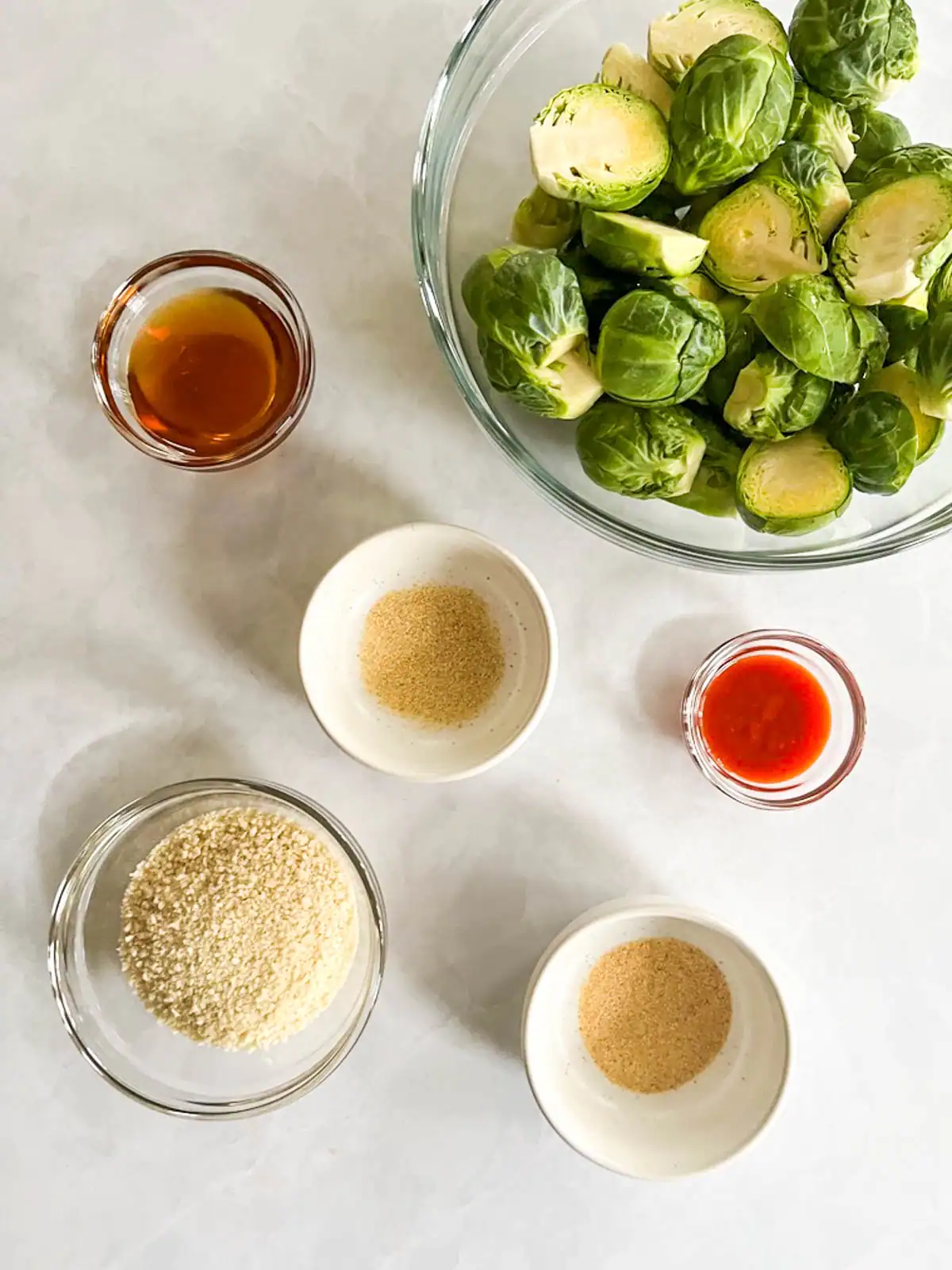 Ingredients for crispy roasted Brussels sprouts with spicy maple glaze in bowls.