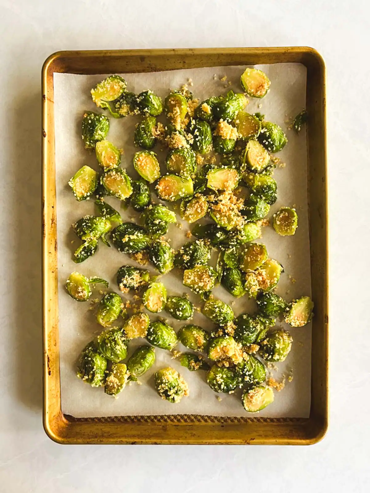 Brussels sprouts tossed in breadcrumbs on a baking sheet.