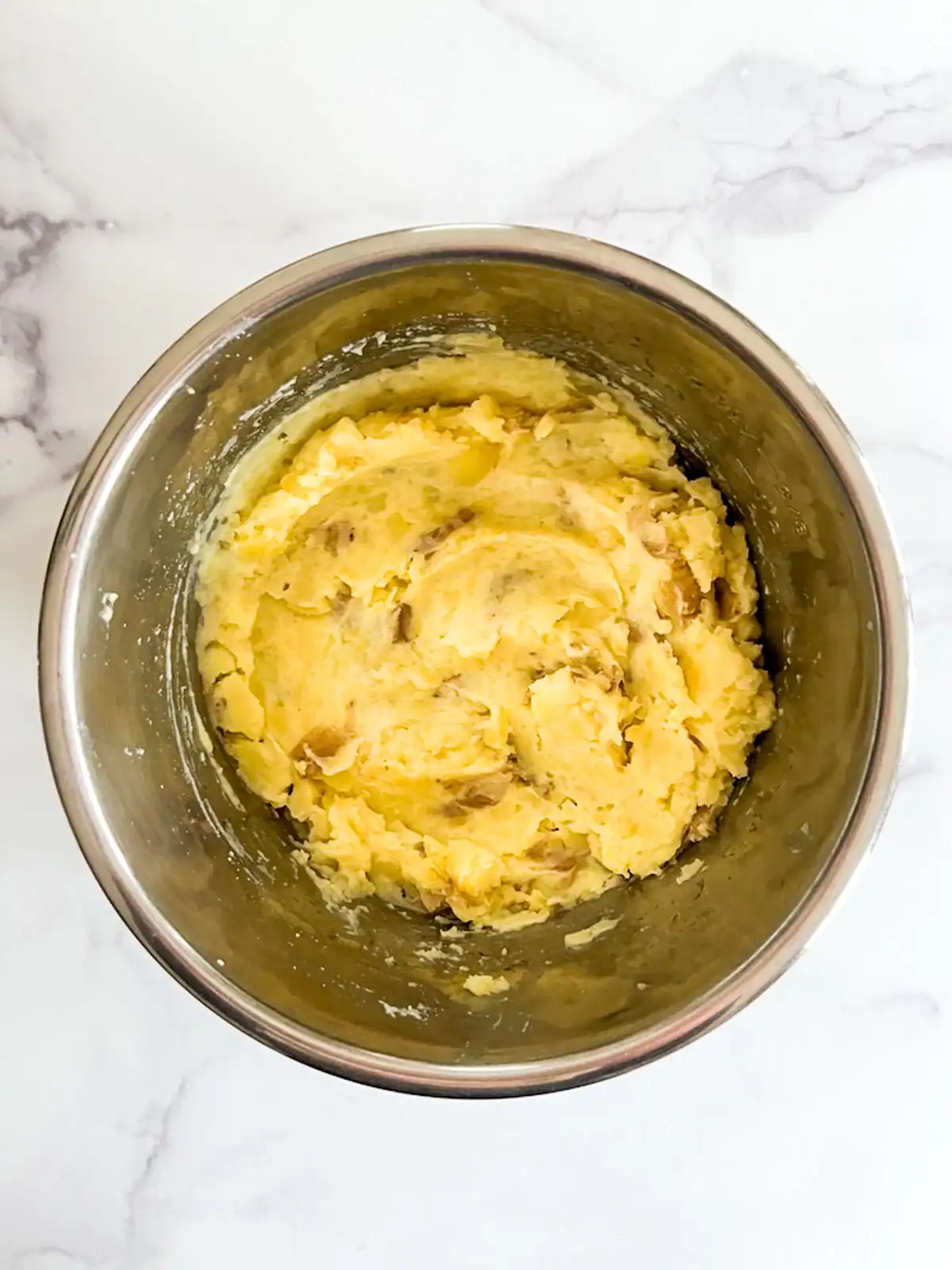 Creamy vegan mashed potatoes with plant-based milk and seasoning added.