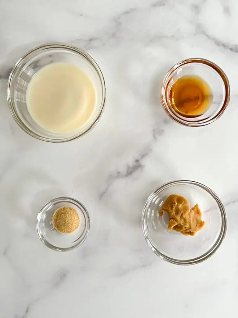 Seasoning ingredients in small glass bowls on marble surface.