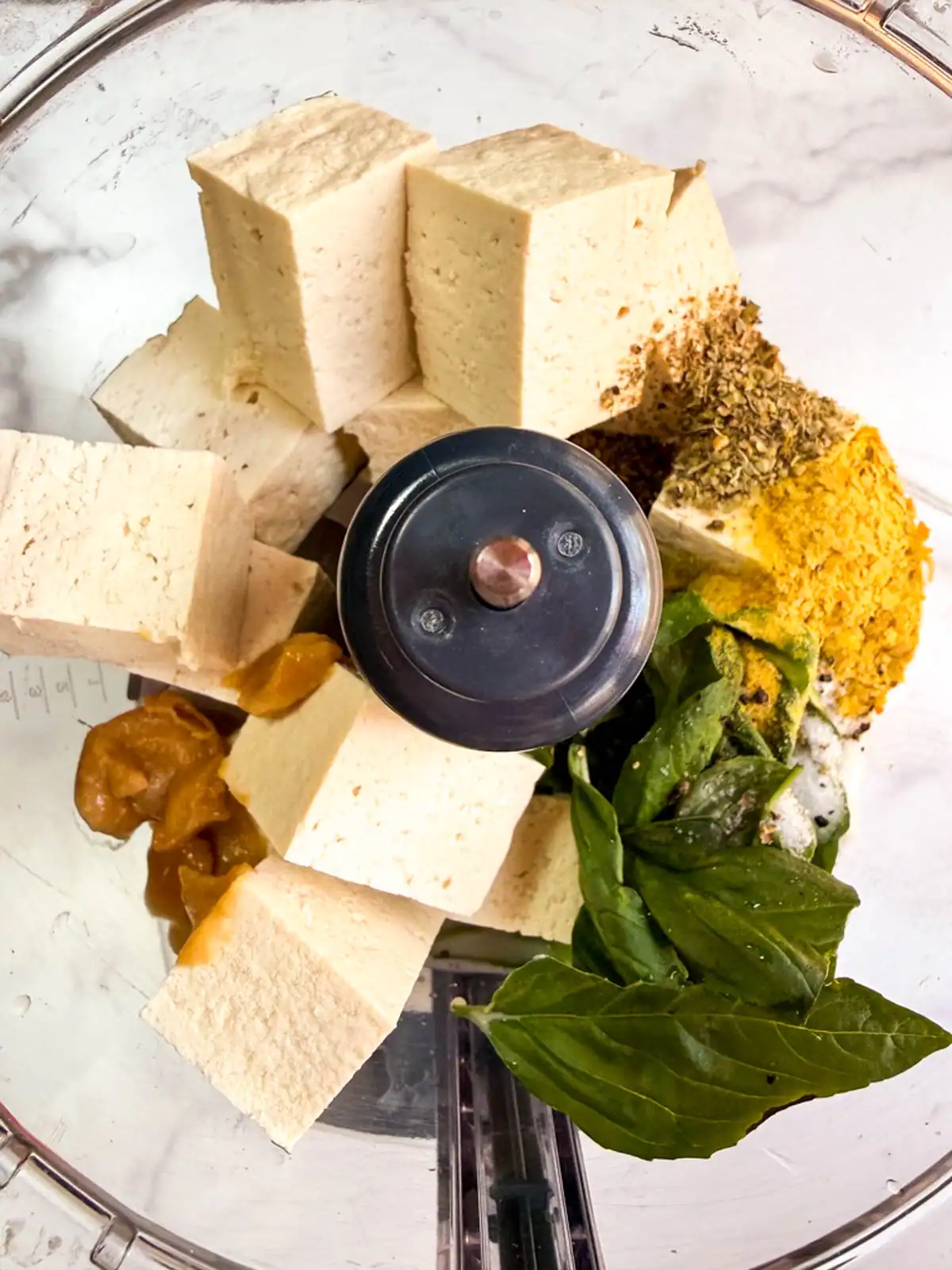 Ingredients for oil-free vegan basil tofu ricotta in a food processor.