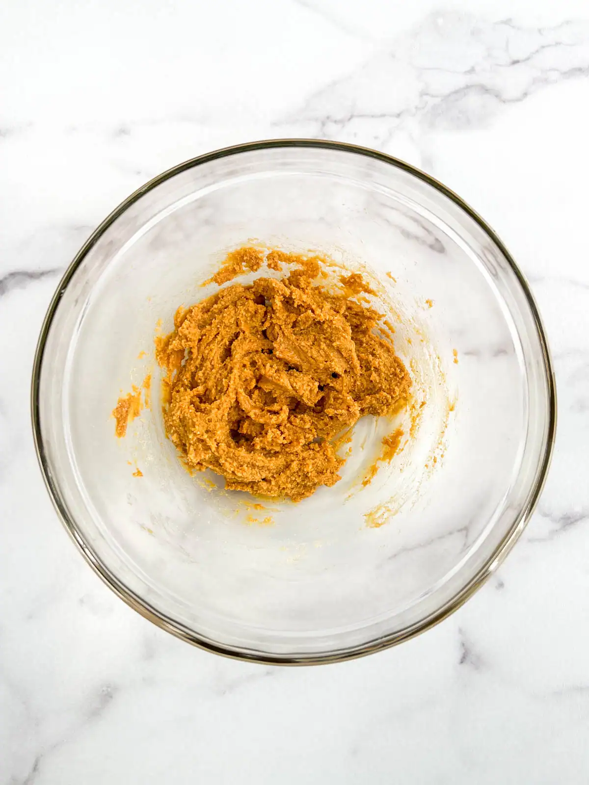 Peanut butter dough in a glass bowl.