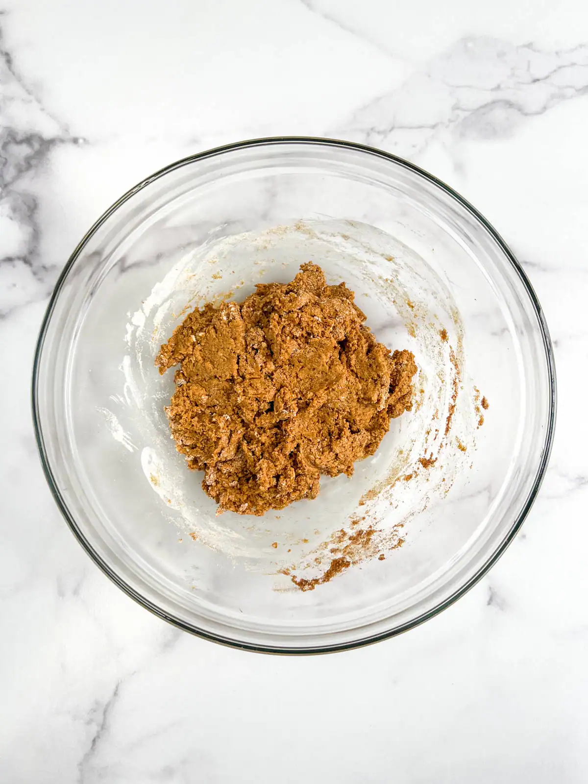 Wet and dry ingredients for vegan ginger pear scones combined in a glass bowl.