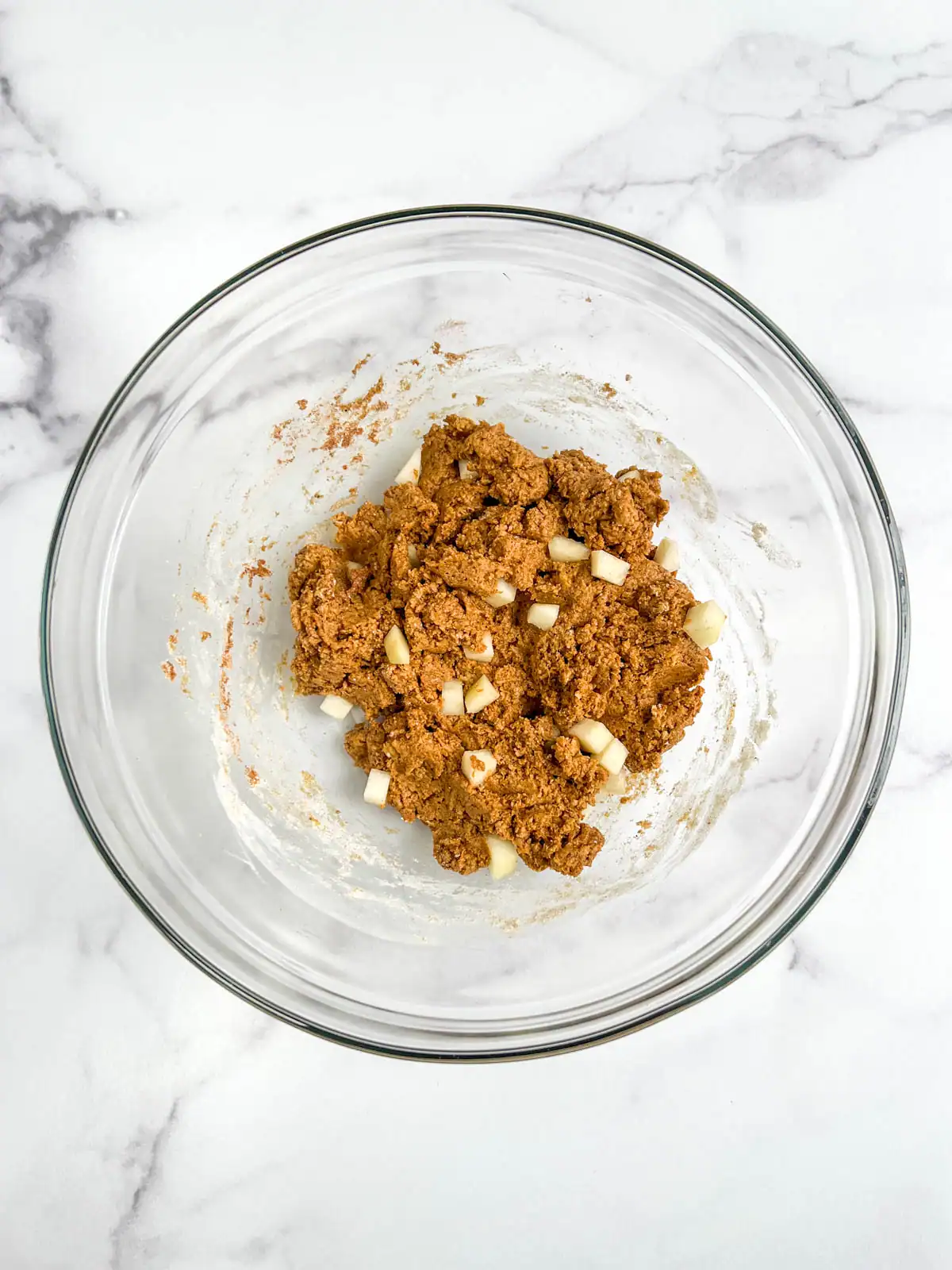 Pear chunks added to batter for vegan ginger pear scones in a glass bowl.