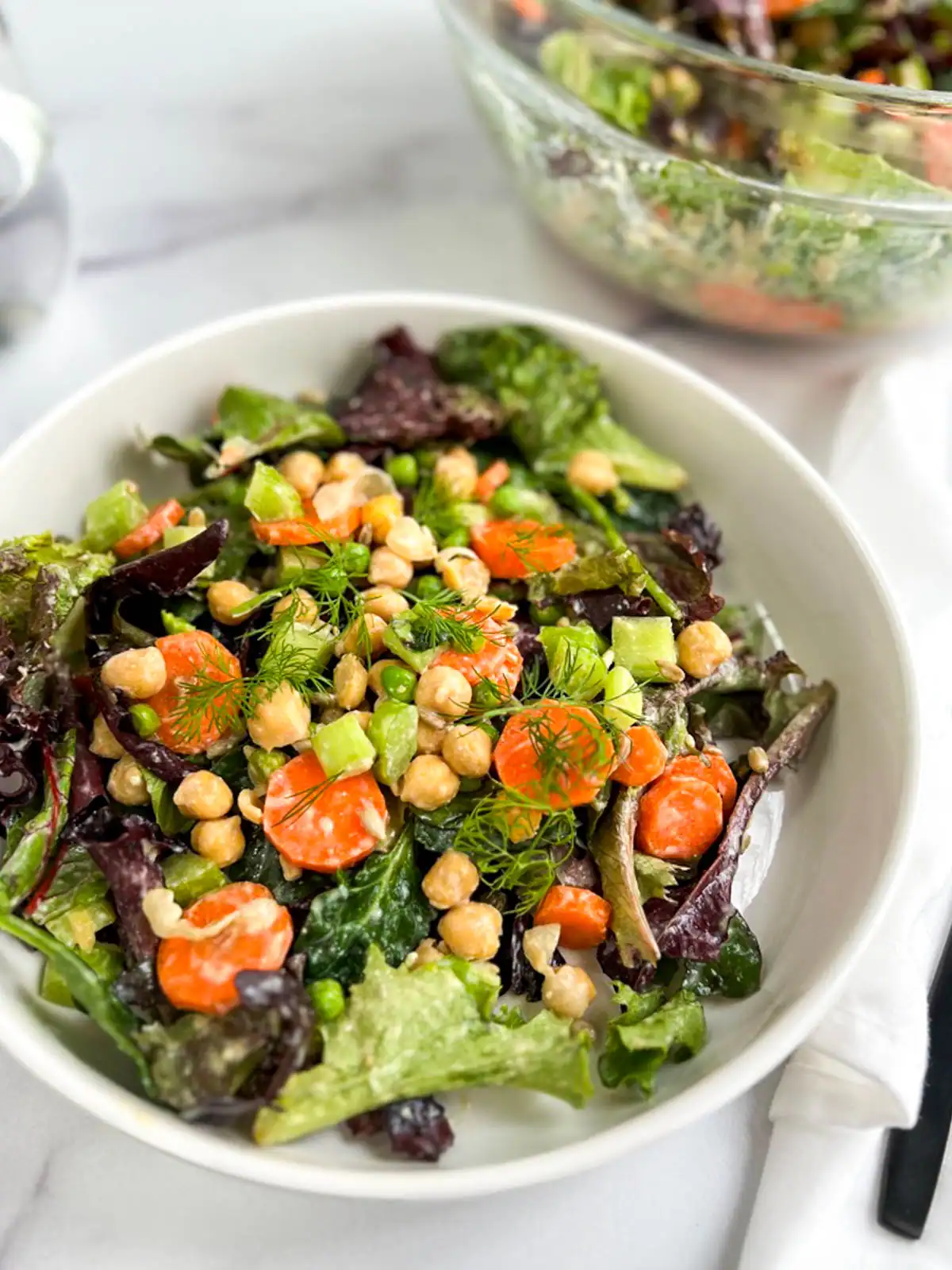 Bowls of chickpea veggie salad with vegan Caesar dressing.