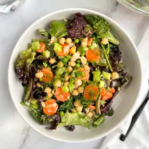 Chickpea veggie salad with vegan Caesar dressing in a white bowl.