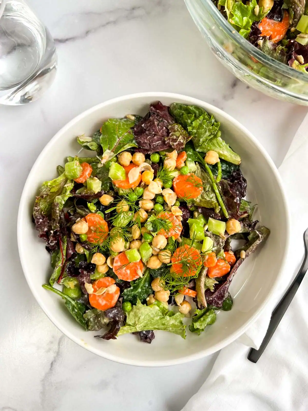 Chickpea veggie salad with vegan Caesar dressing in a white bowl.
