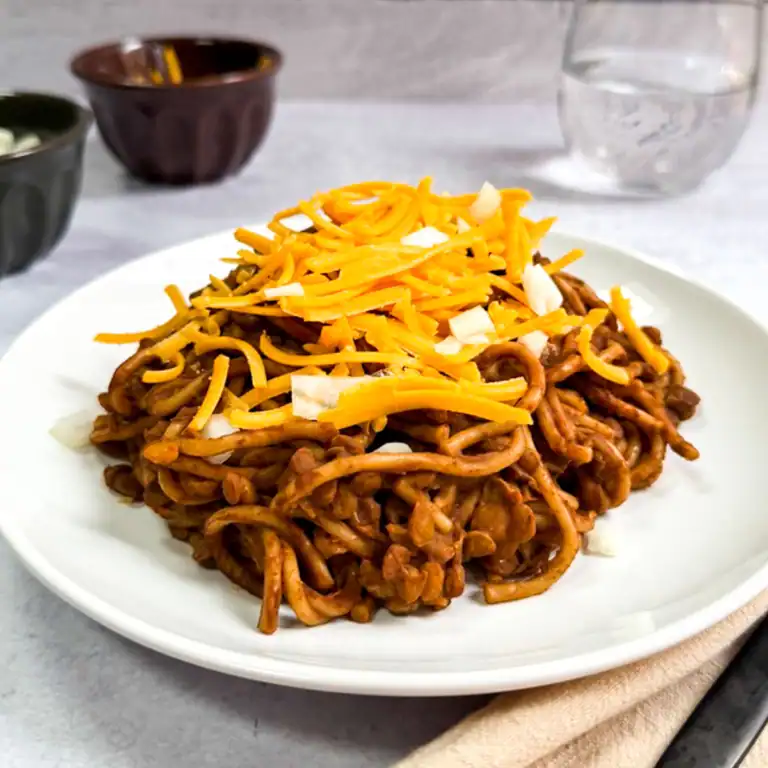 Instant Pot Cincinnati chili topped with shredded vegan cheese and diced onions.