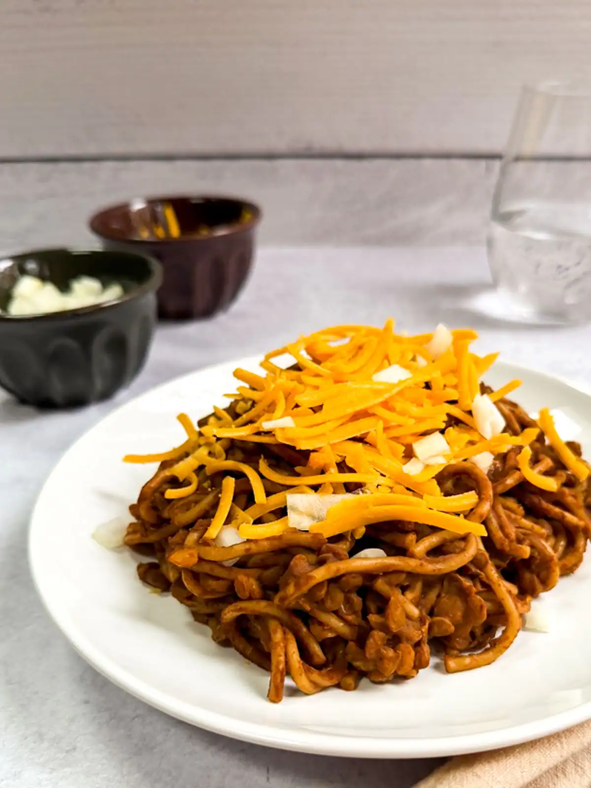 Instant Pot Cincinnati chili topped with shredded vegan cheese and diced onions.