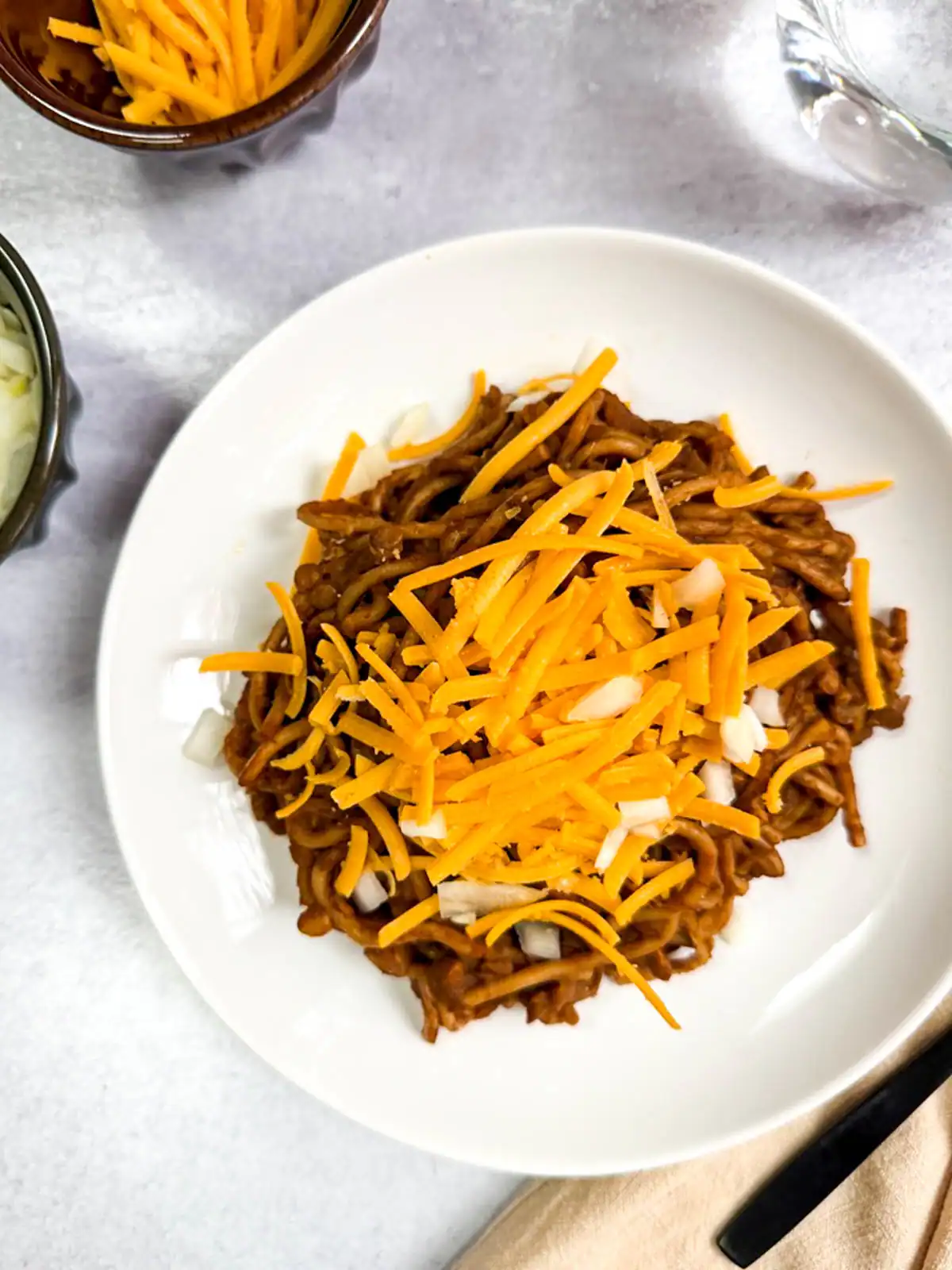 Instant Pot Cincinnati chili topped with shredded vegan cheese and diced onions.