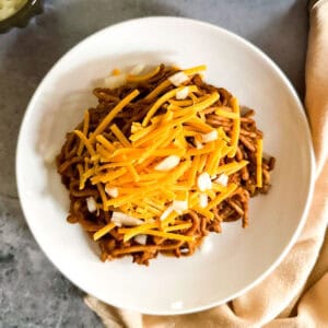 Instant Pot Cincinnati chili topped with shredded vegan cheese and diced onions.