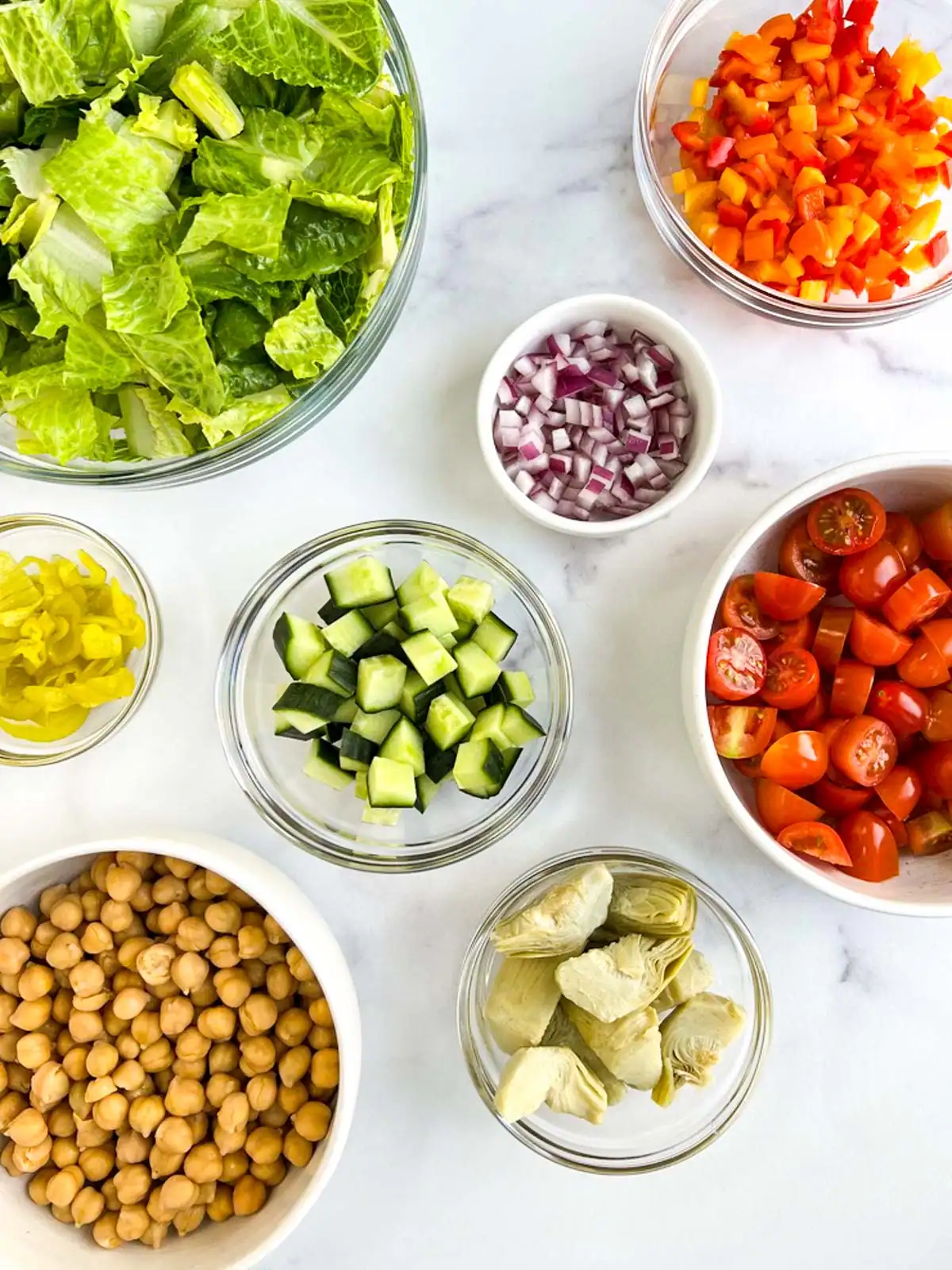 Ingredients for Italian chopped salad on a marble surface.