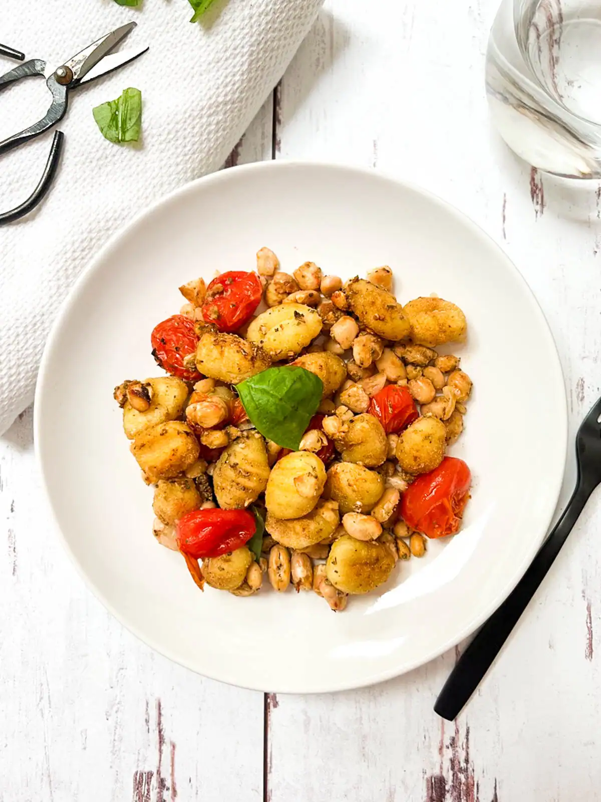Gnocchi with blistered tomatoes and white beans in a bowl.