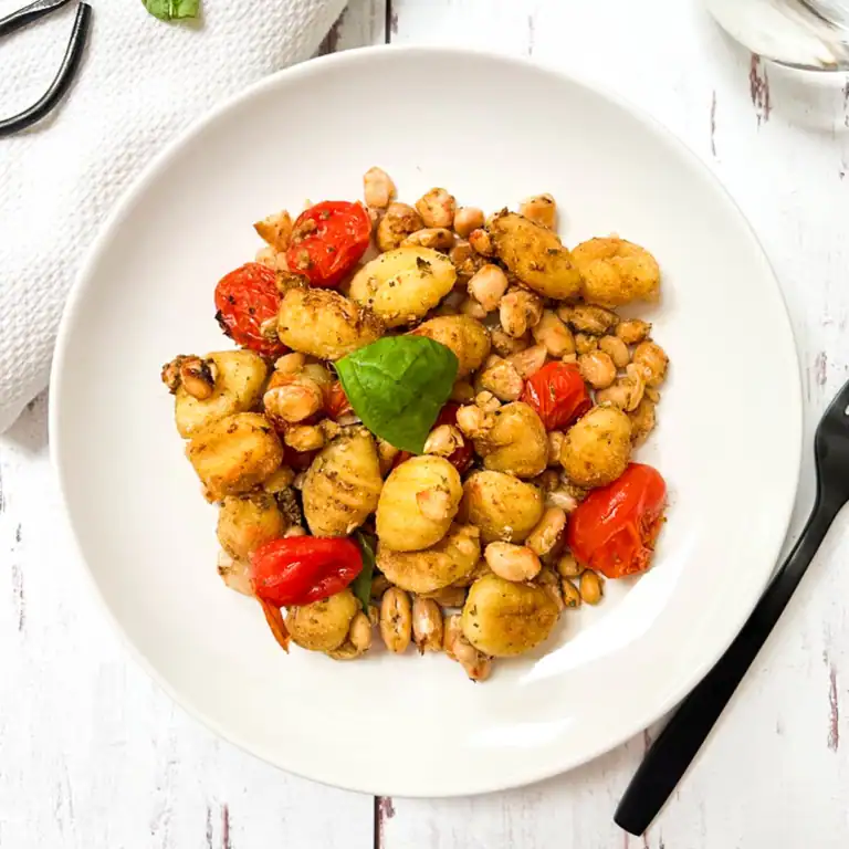 Gnocchi with blistered tomatoes and white beans in a bowl.