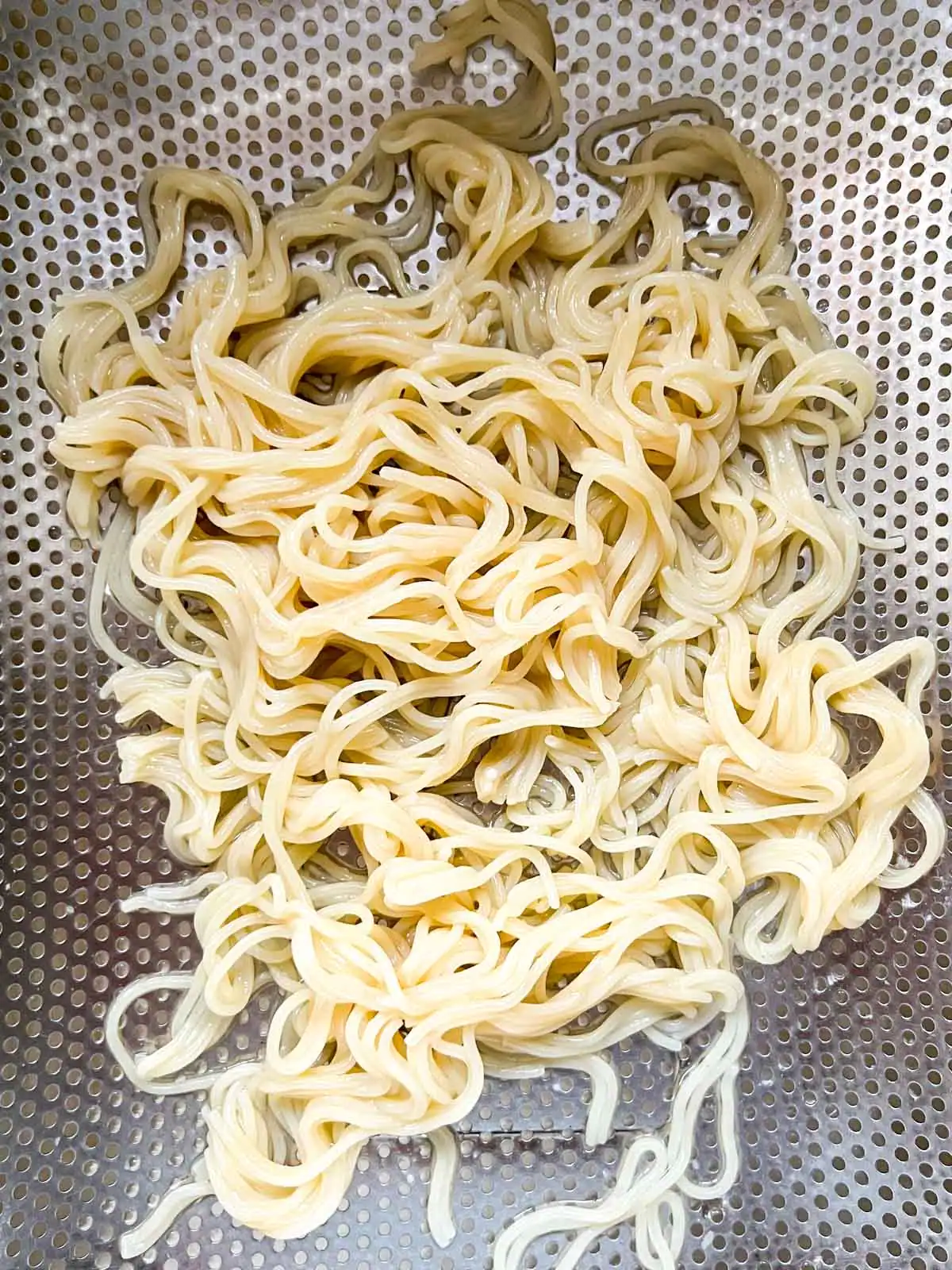 Cooked ramen noodles in a colander.