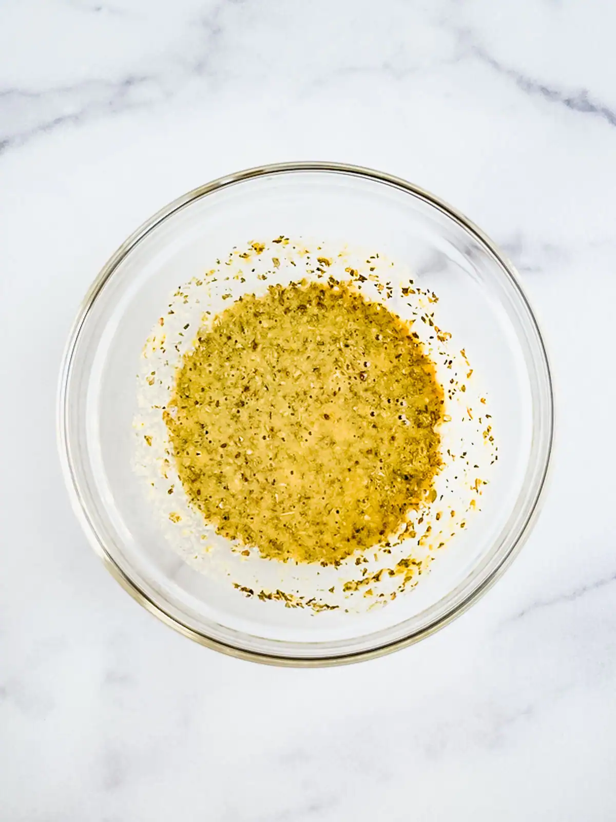 Oil-free Italian dressing in a glass bowl on a marble surface.