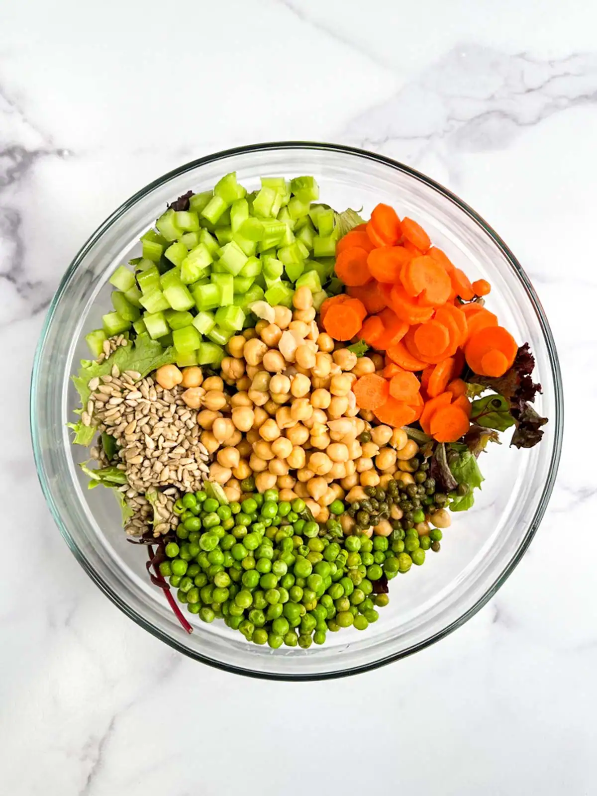 Ingredients for chickpea veggie salad in a glass bowl.
