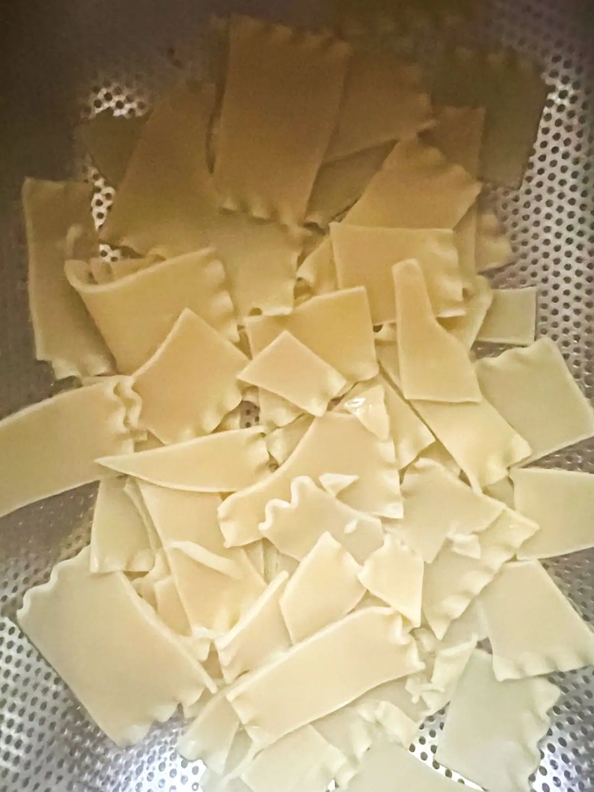 Cooked lasagna noodles draining in a colander.