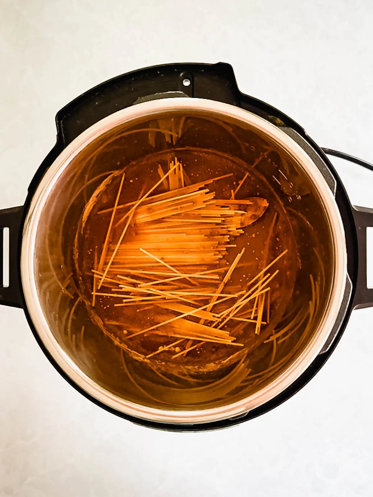 Spaghetti added to Cincinnati chili sauce ingredients in Instant Pot.