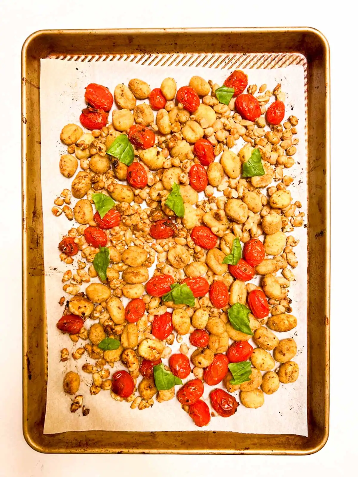 Sheet pan gnocchi with blistered tomatoes and white beans on a baking sheet.