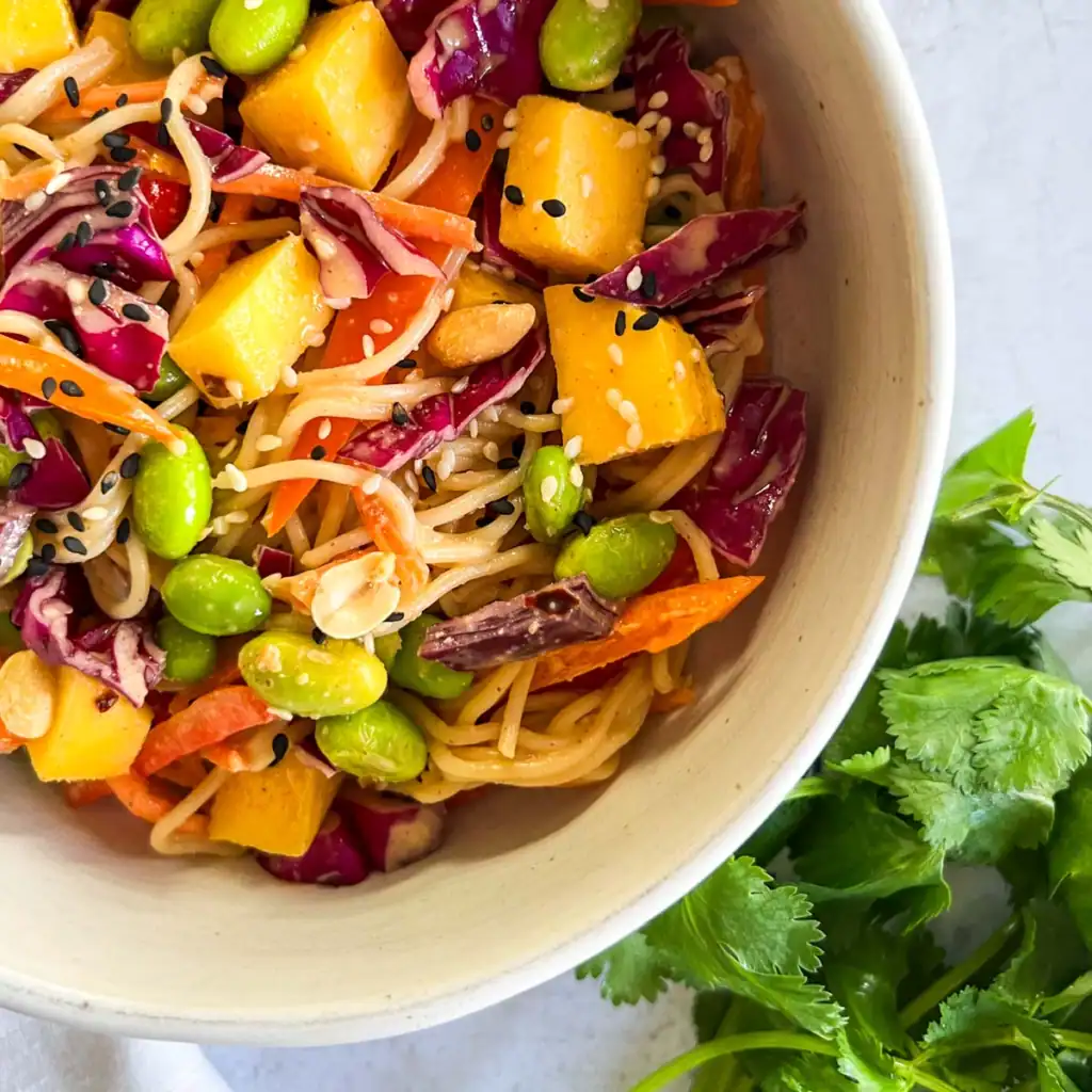 Mango peanut noodle salad in a bowl with fresh cilantro.