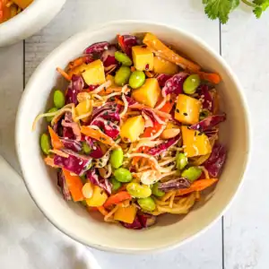 Mango peanut noodle salad in a white bowl.